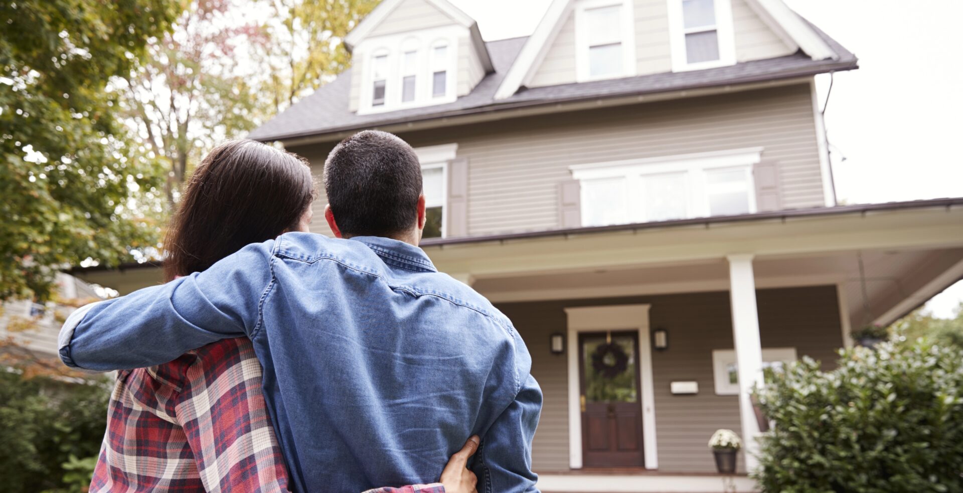 happy couple hugging and looking at their new home