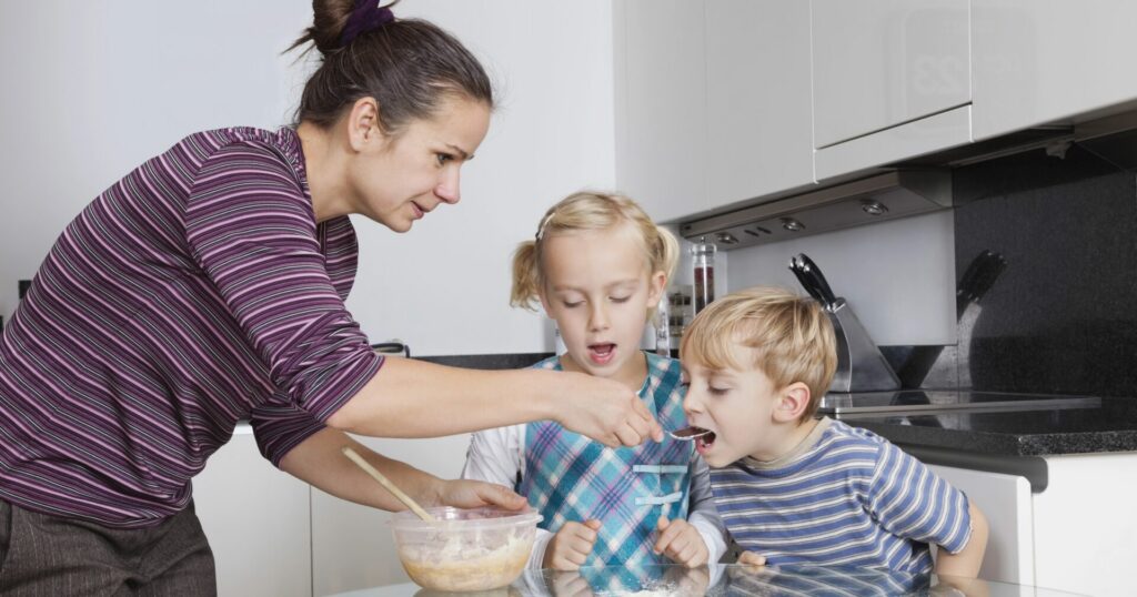 mom feeding her two kids food on a spoon